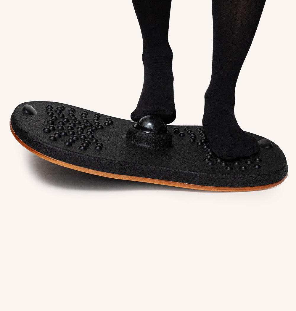 Person balancing on a Standy Balance Board, promoting active standing and improving core strength.