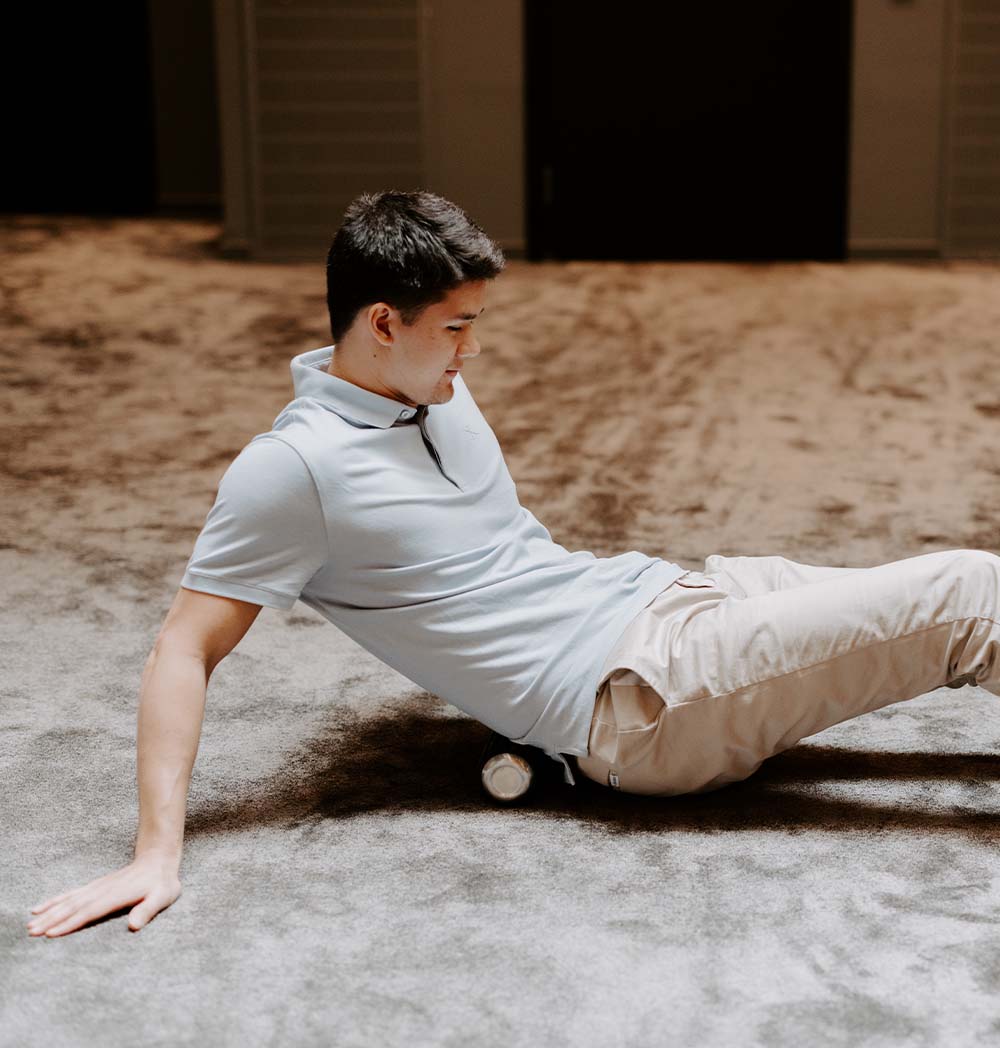 Mężczyzna korzysta z wałka do masażu na miękkiej podłodze, relaksując się i rozluźniając mięśnie.