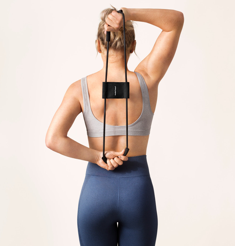 Woman using Trainer 3w1 stretch band for posture correction and muscle flexibility.